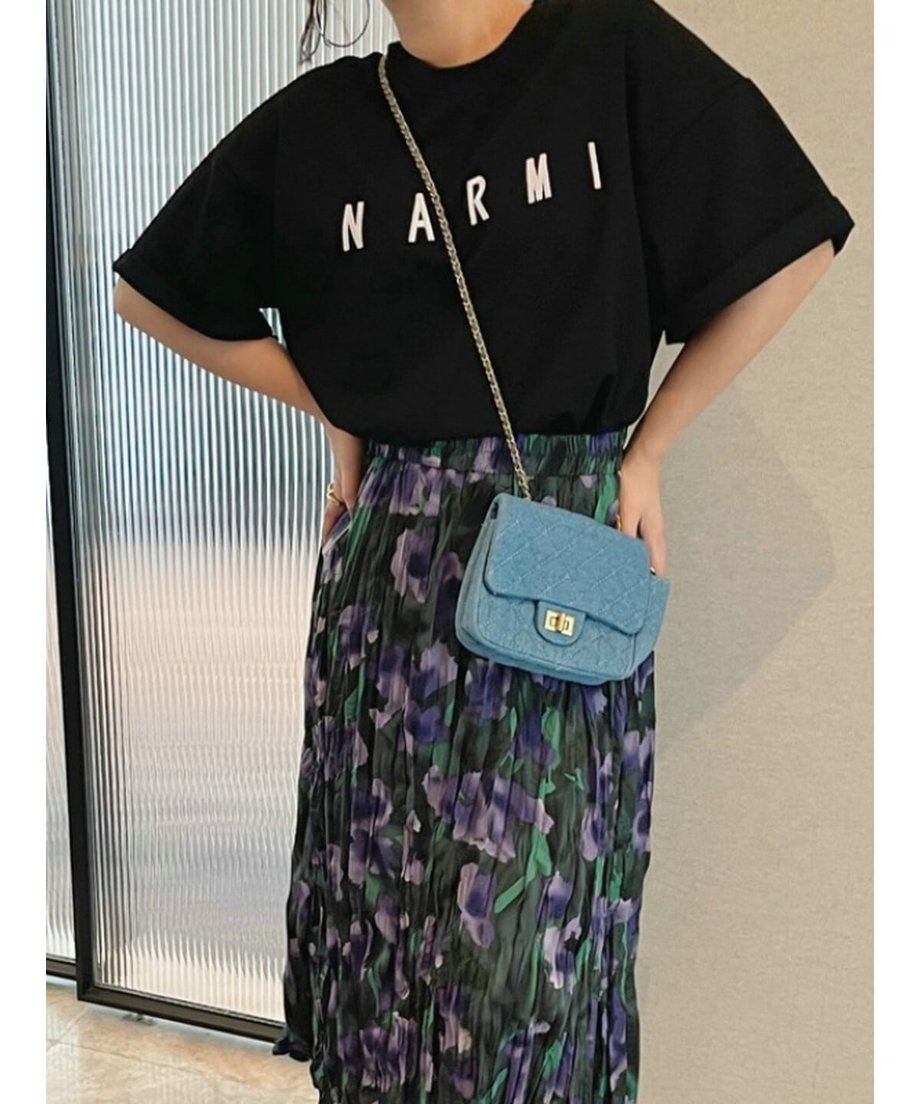 ブラックのロゴTシャツを、緑と紫の花柄プリーツスカートにタックインした大人カジュアルな着こなし。
