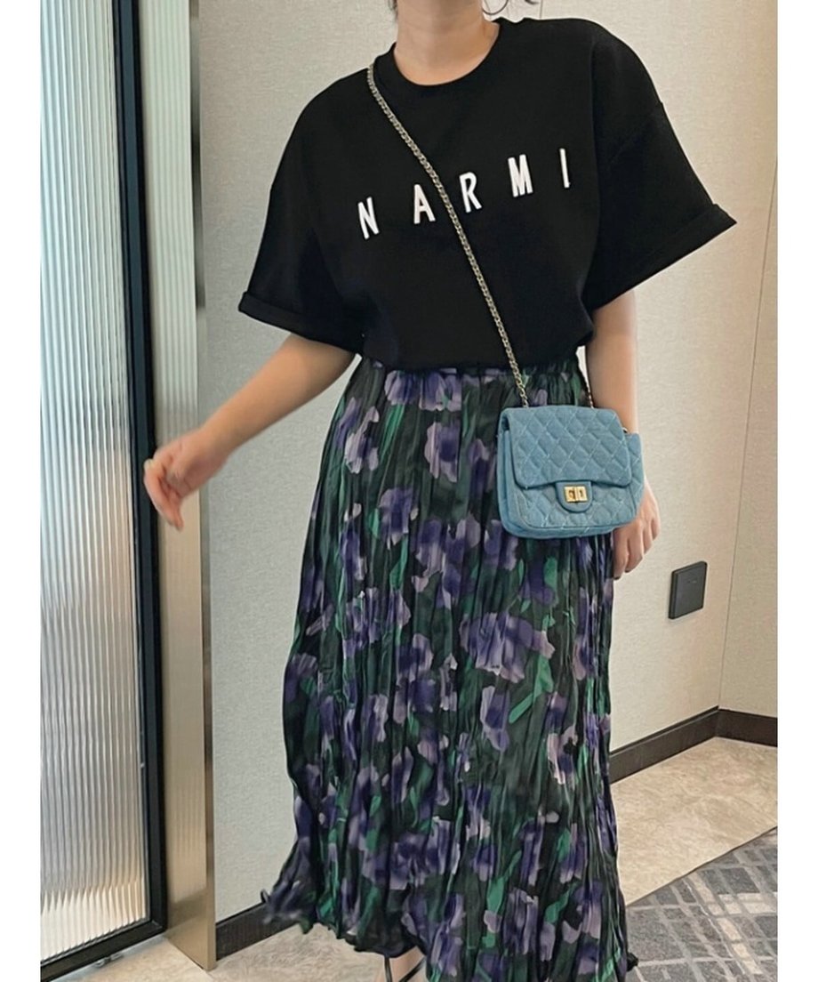 花柄スカートとブラックのロゴTシャツに、ブルーのキルティングチェーンバッグを合わせた華やかなスタイリング。