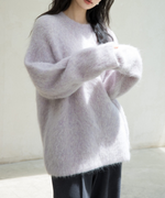 パープルのニットを着用した女性伸ばすとアップ。黒いボトムスとコーディネートしている写真。