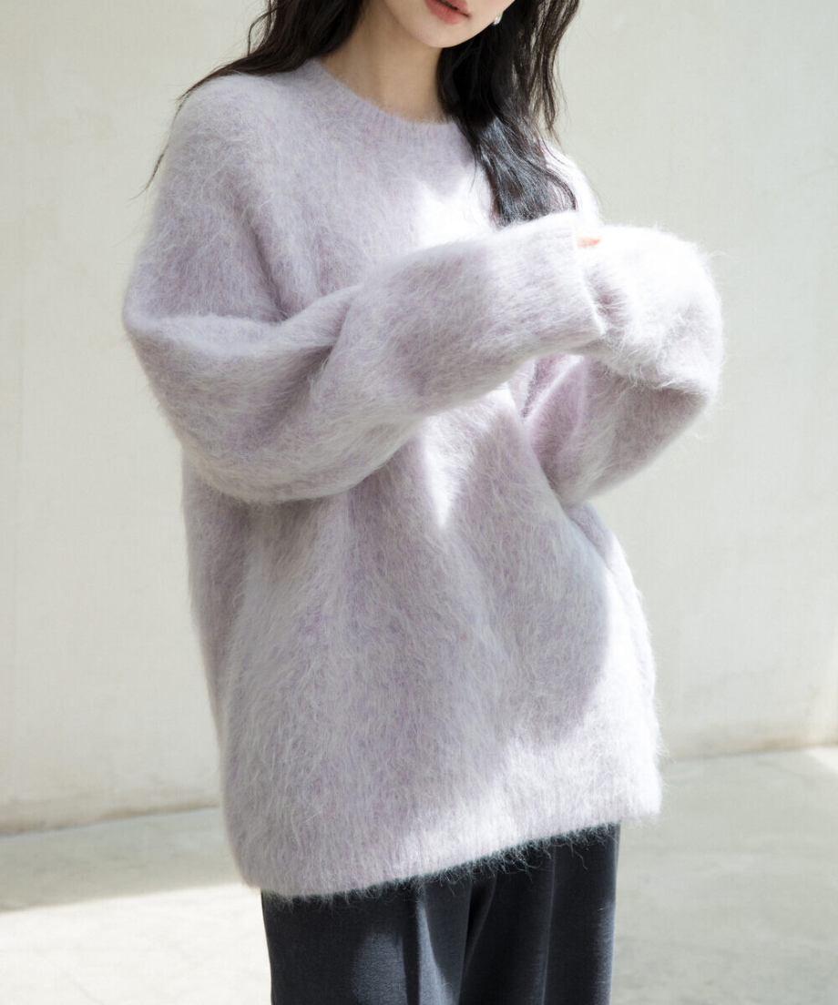 パープルのニットを着用した女性伸ばすとアップ。黒いボトムスとコーディネートしている写真。