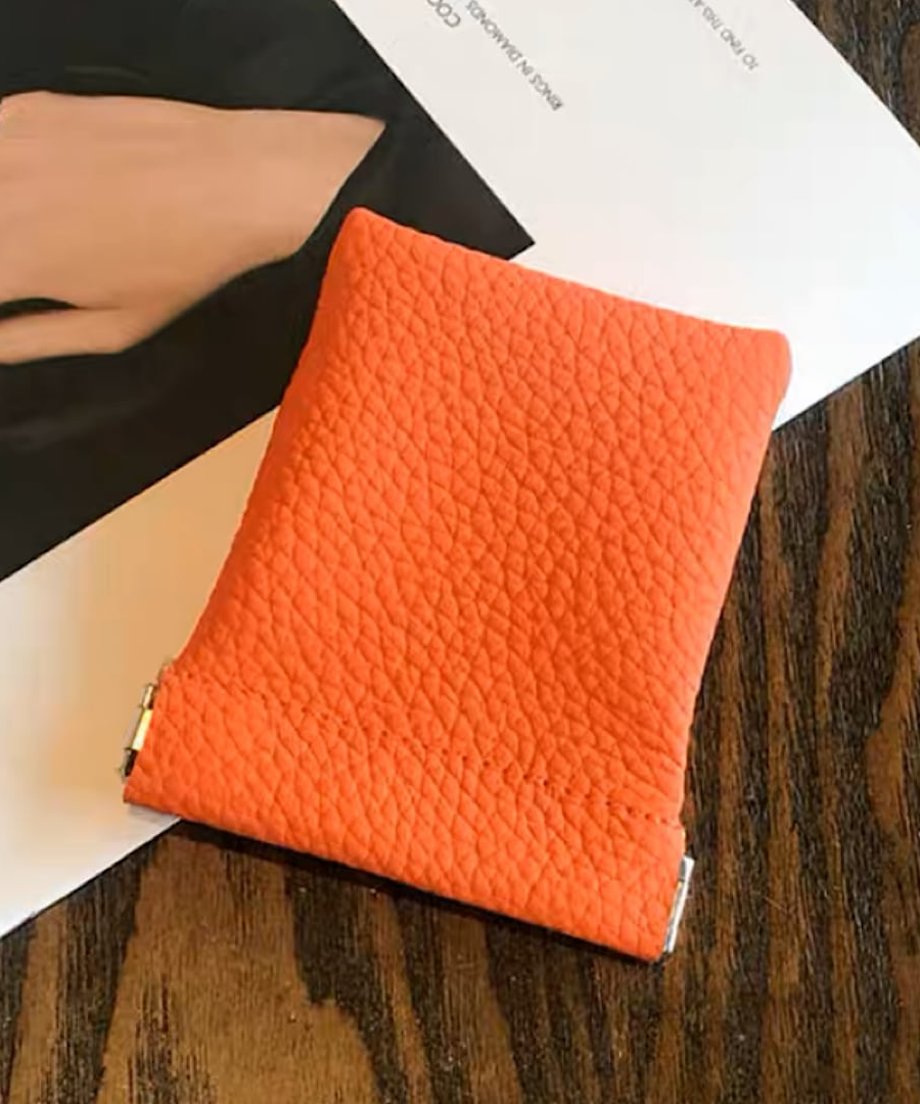 シボ加工が施されたオレンジ色のレザーポーチの全体像。