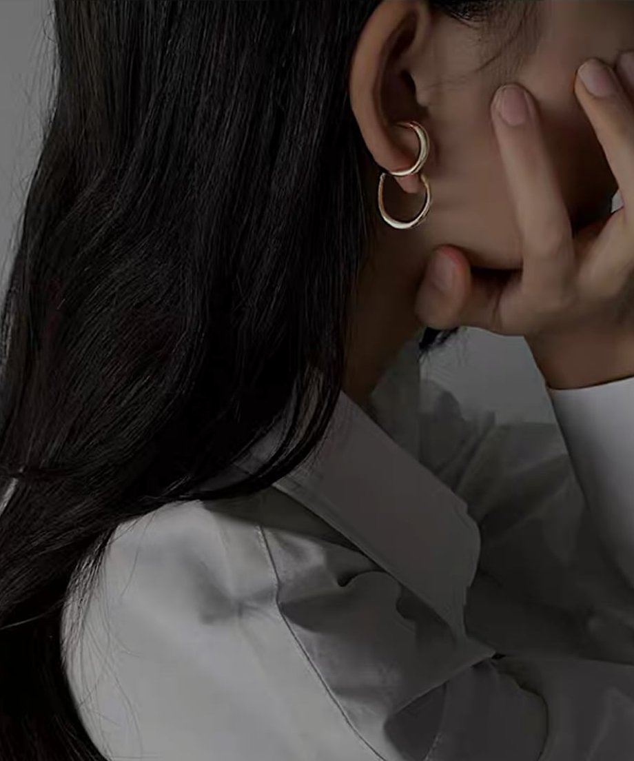 耳元で緩やかな曲線を描くゴールドの変形フープピアスを着用した女性の横顔