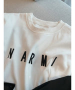 ホワイトのTシャツ生地に施された、光沢のある黒い立体刺繍ロゴ「NARMI」のクローズアップ。