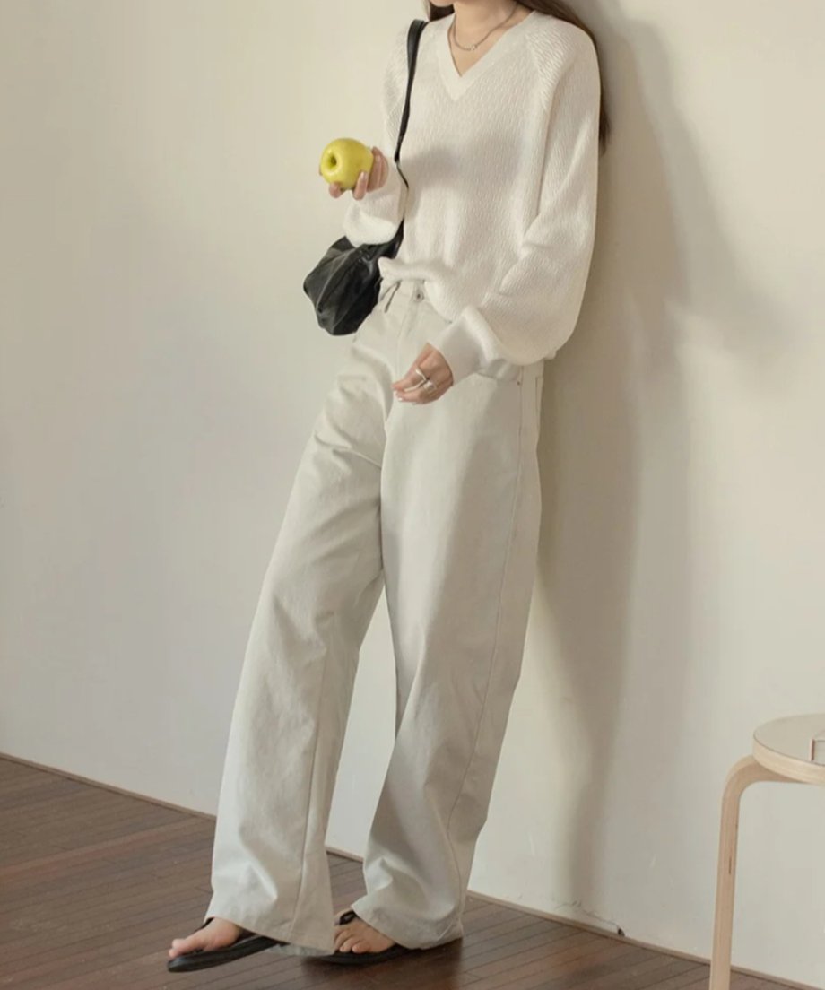 ライトグレーのワイドレッグパンツに白いセーターを合わせたコーディネート。