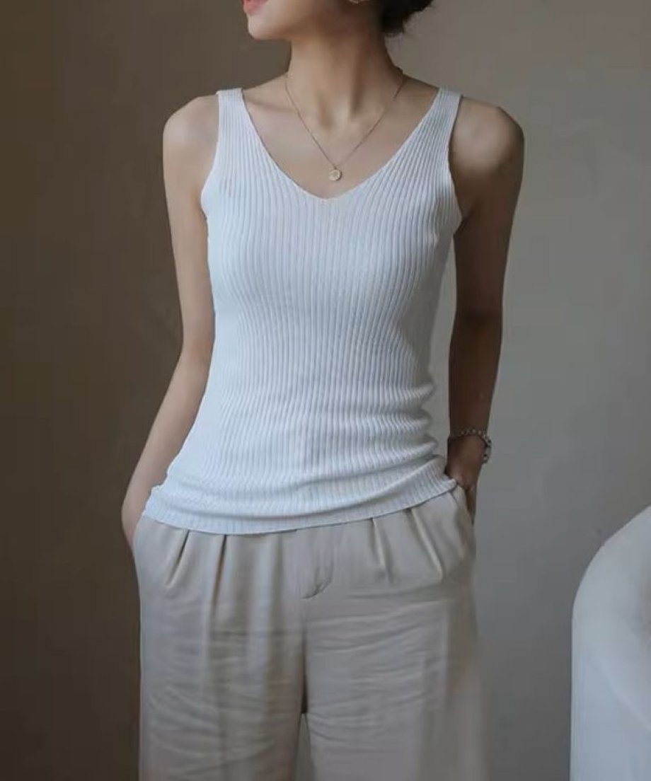 白いリブタンクトップを着た女性がベージュのパンツを合わせている画像。