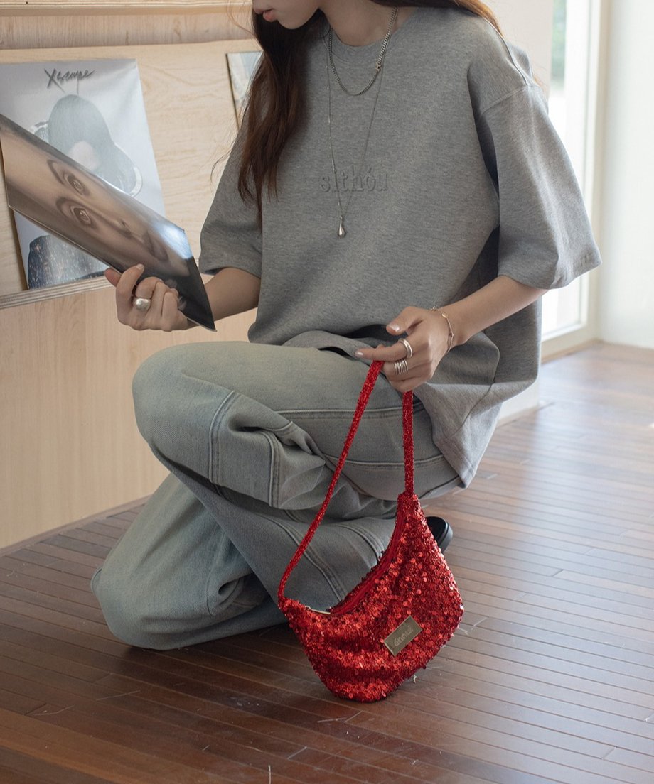 グレーのロゴTシャツと赤いバッグを持ったカジュアルスタイルの女性