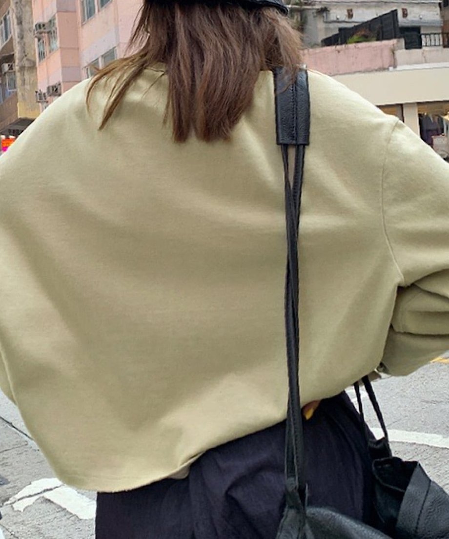 ベージュのダメージ加工プルオーバーを背面から捉えた、広めの身幅とリラックス感のあるバックスタイル。
