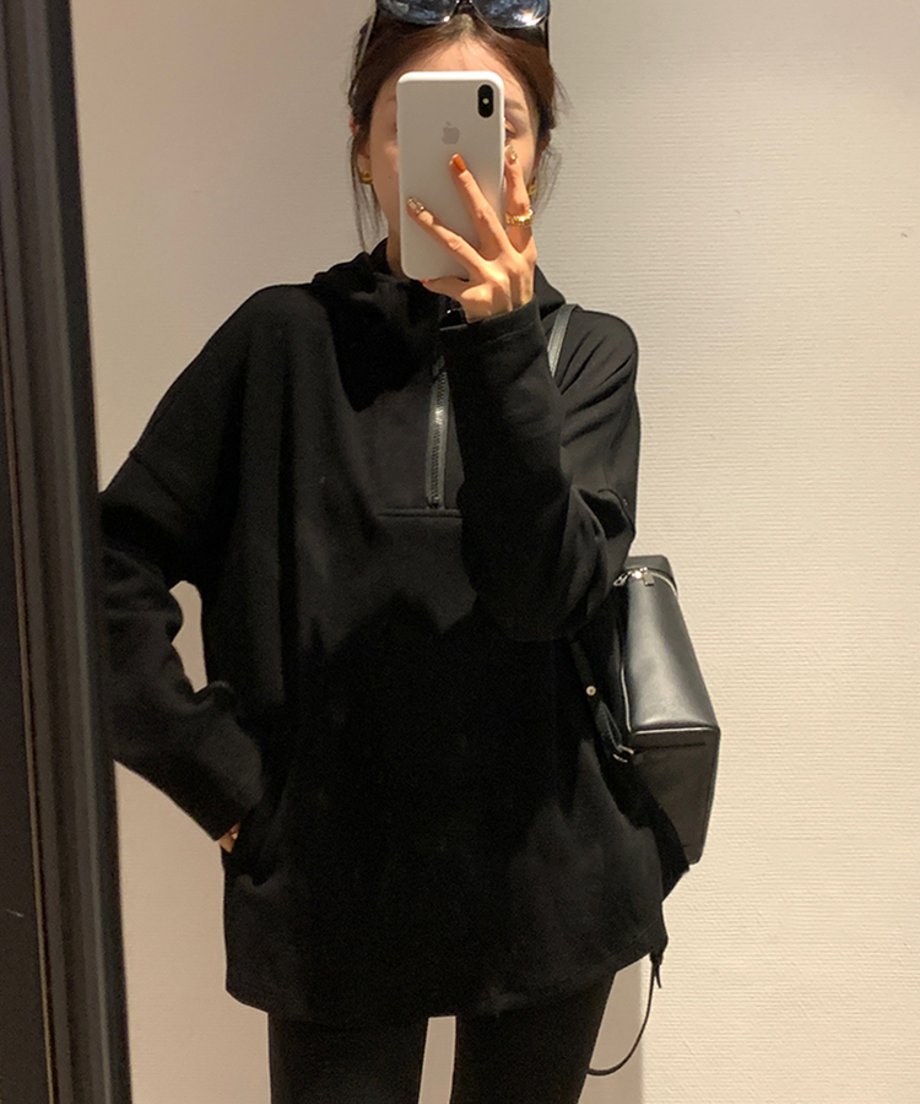 ブラックのオーバーサイズフーディーを着用し、サングラスを頭に乗せて鏡越しに撮影している女性。フロントにはジップとカンガルーポケットのディテールが見える。