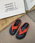 レッドのサンダルがカーペット上に置かれた画像。