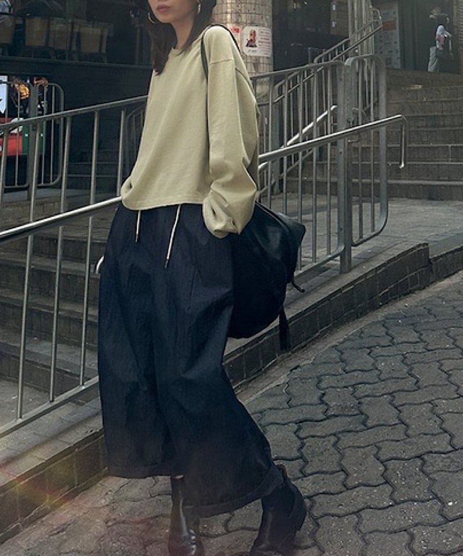 ベージュのダメージ加工プルオーバーに黒のワイドパンツとブーツを合わせた、ストリート感のある全身スタイリング。