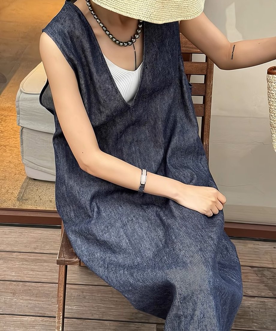 深いVネックのブルーのデニムドレスを着た女性が椅子に座っている。