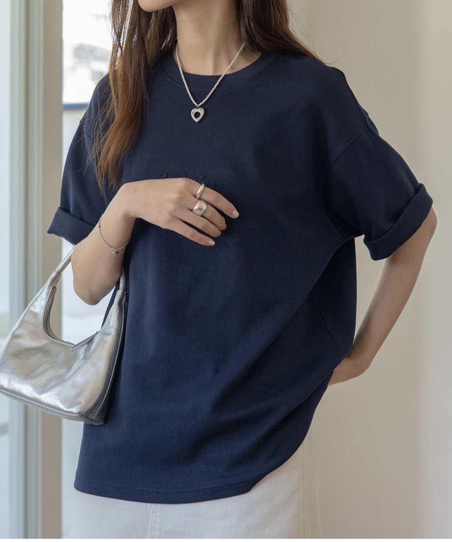 ネイビーのTシャツを着た女性がシルバーのバッグを持っている様子。
