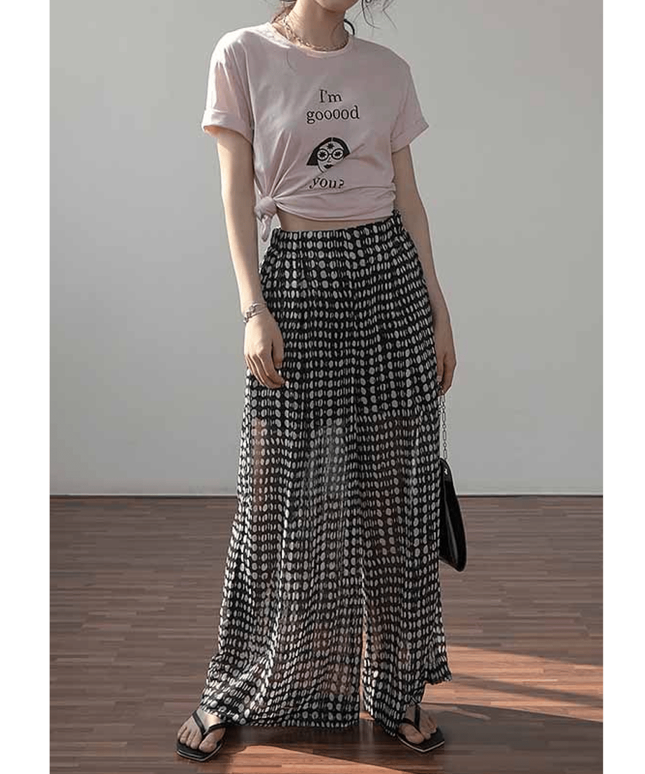 ピンクのグラフィックTシャツをウエストで結び、ハイウエストドット柄ワイドパンツを合わせた、リラックス感のある夏のレディースコーディネート。