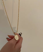 指に添えられた、ひまわりの彫刻が細部まで美しいゴールドのオーバルチャーム。