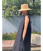 黒のロングワンピースを着て横を向いた女性。ポケットに手を入れたリラックスしたポーズ。