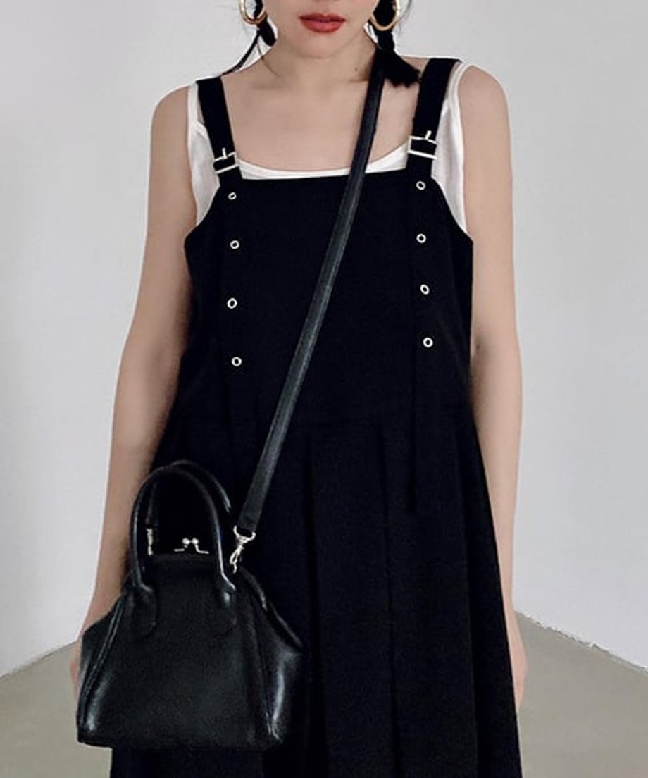 黒のサスペンダーロングワンピースに白のタンクトップをインナーにした女性の胸元ショット。