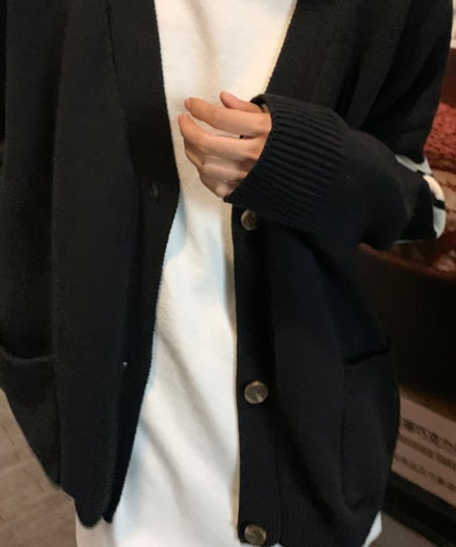 黒いライン入りオーバーサイズカーディガンの袖口とフロントのボタンをクローズアップした写真。