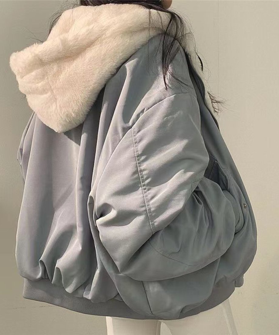ブルーのナイロン面を表にして着ている女性の側面からの写真。内側の白いボアと、フード部分にボリュームがある