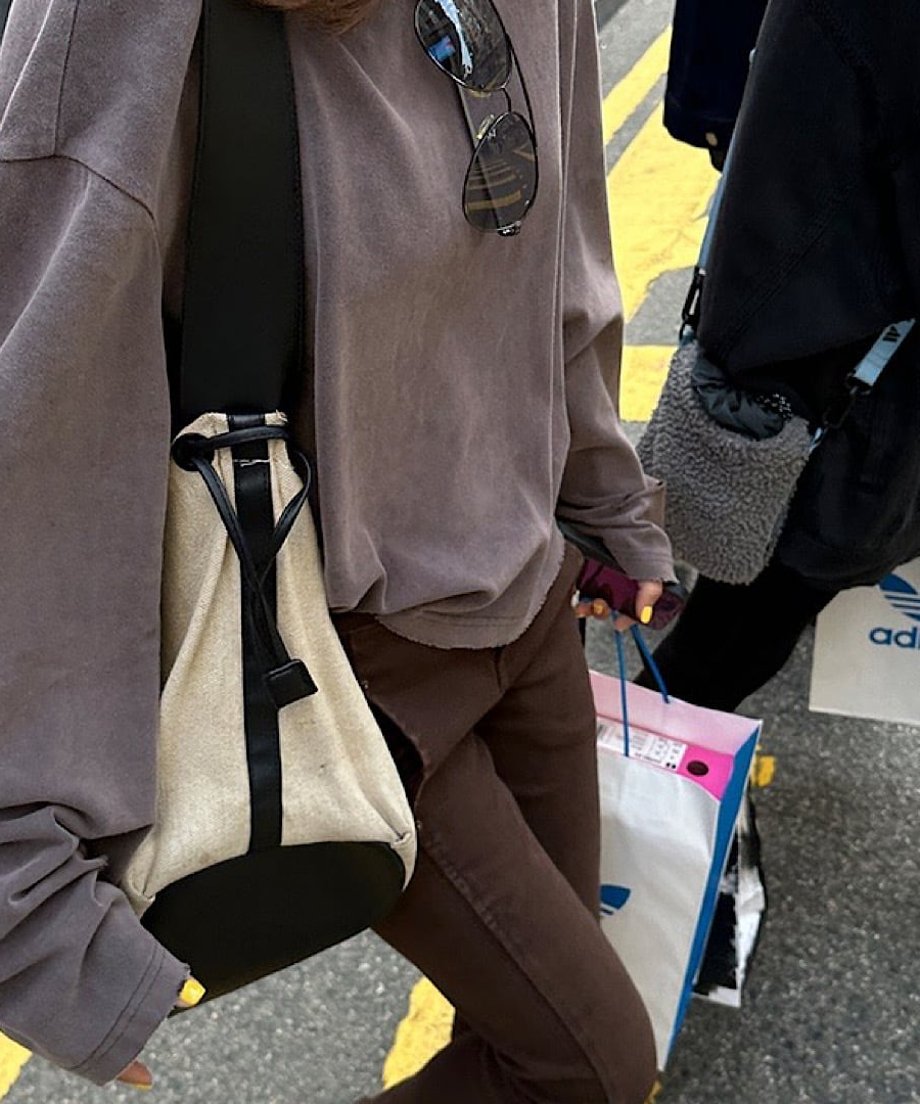 グレーブラウンのダメージ加工プルオーバーとブラウンのパンツを合わせた、街歩きシーンのウエストライン付近のカット。
