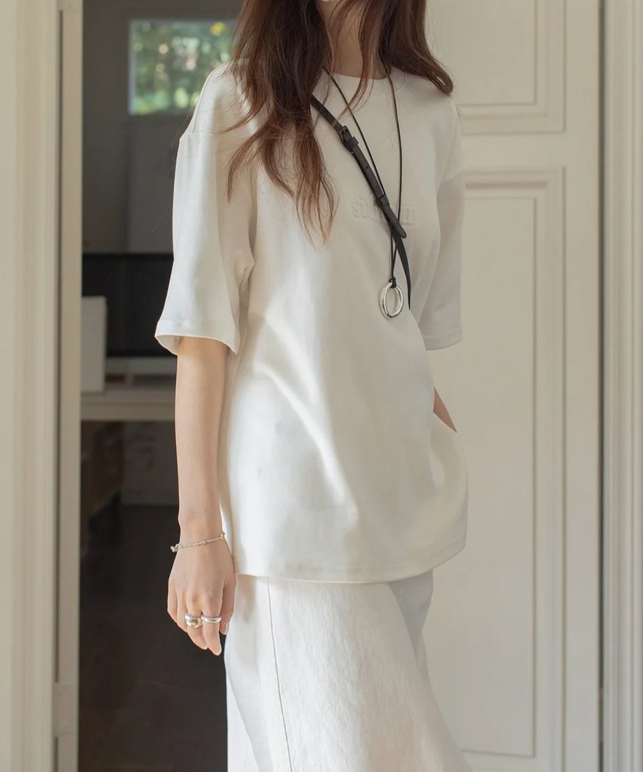 オフホワイトのTシャツを着たモデルが、シンプルでスタイリッシュなコーディネートを披露。