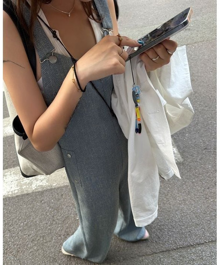 ブルーのワイドレッグオーバーオールのフロントディテール。胸元のストレートなカッティングと、白のシャツを羽織ったスタイリング。