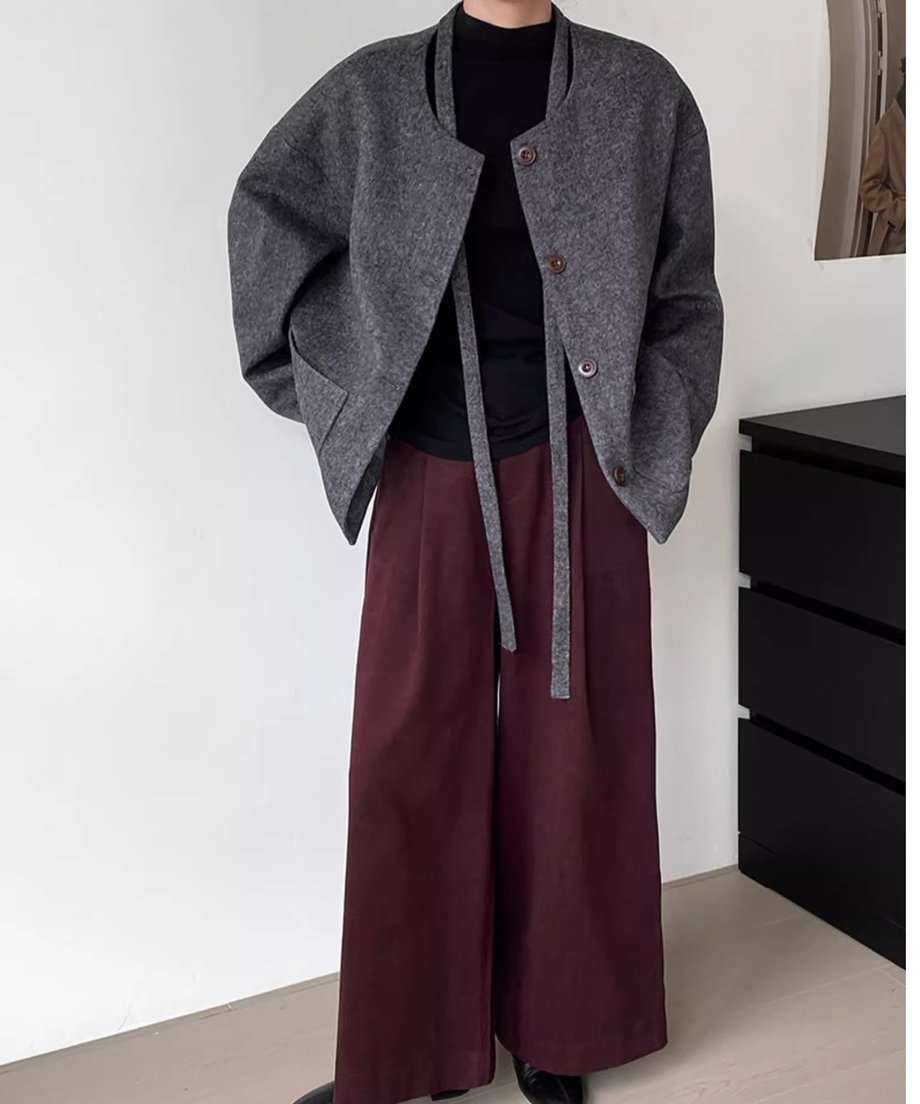 グレーのウールショートコートを前開きで着用した女性の全身像。コートのベルトを長く垂らし、ワインレッドのワイドパンツを着用。