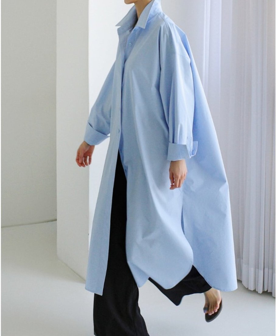 ブルーのロングシャツを羽織り、黒のパンツと合わせた歩行時の動きがあるカット。