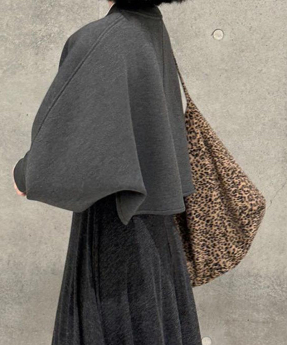 ークグレーのクロップドトップスとロングスカートを着用した女性の斜め後ろからの写真。トップスはボリュームスリーブで、レオパード柄の大きなバッグをかけている。