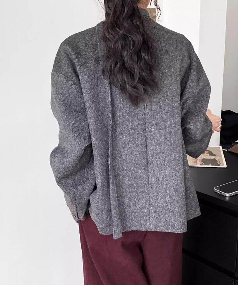 グレーのウールショートコートを着用した女性の後ろ姿。ゆったりとしたAラインのシルエットとドロップショルダーが確認できる。