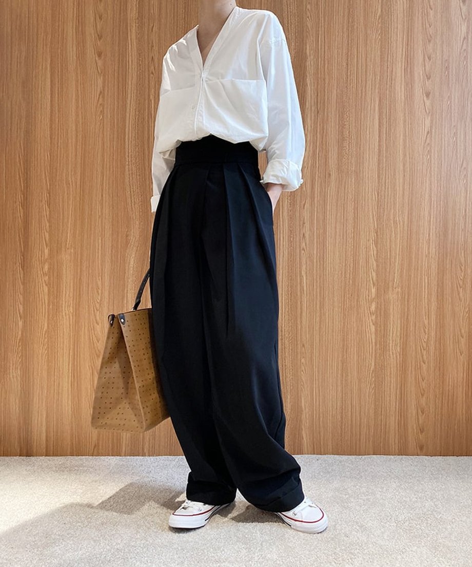 ブラックのハイウエストワイドタックパンツを白いシャツと白いスニーカーに合わせ、茶色の大きなトートバッグを持つ全身コーディネート。