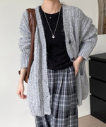 グレーのケーブルニットロングカーディガンを着用した上半身。黒のインナーとチェック柄パンツに、茶色のショルダーバッグを肩掛け。ポケットに手を入れたポーズ。