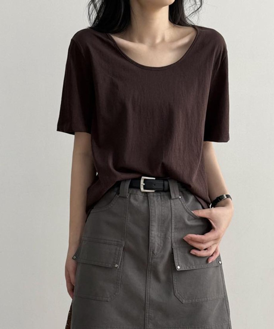 ブラウンのUネックTシャツを着用した女性の上半身。Tシャツをグレーのカーゴポケット付きミニスカートにタックインし、黒いベルトを締めている。