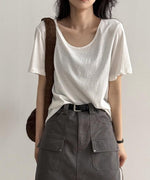 ホワイトのUネックTシャツを着用した女性の上半身。Tシャツをグレーのカーゴポケット付きミニスカートに軽くタックインし、黒いベルトを締めている。