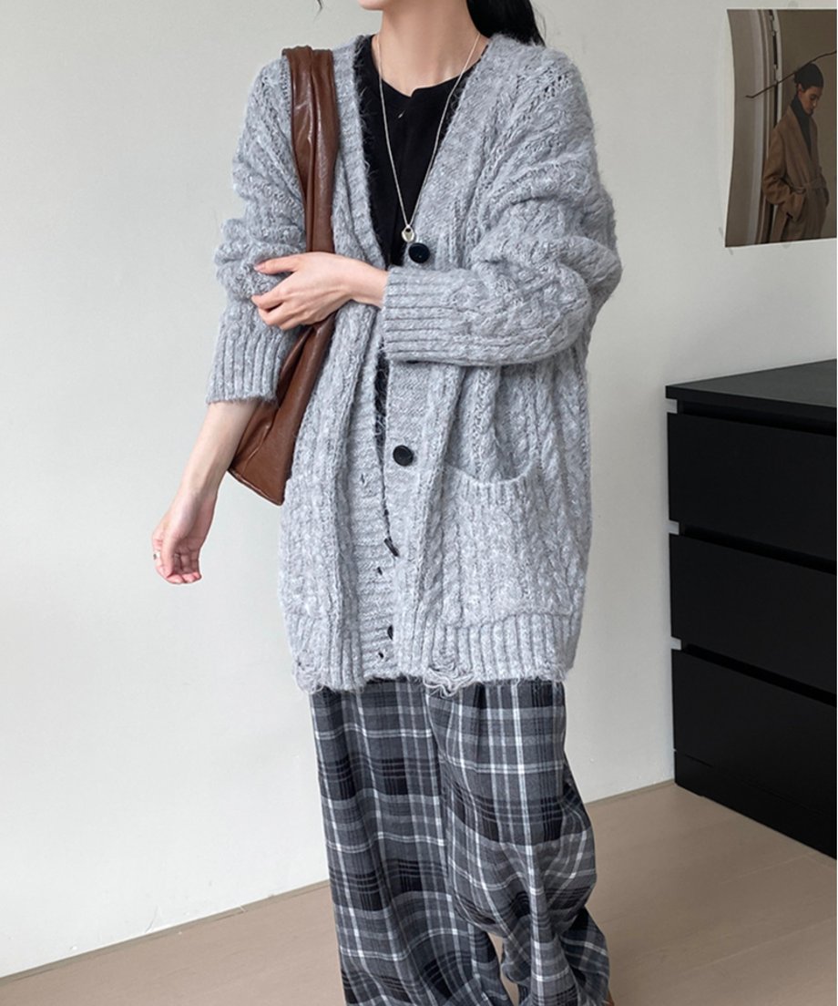 グレーのケーブルニットロングカーディガンを着用した全身。黒のインナーとグレーのチェック柄ワイドパンツ、茶色のショルダーバッグを合わせている。