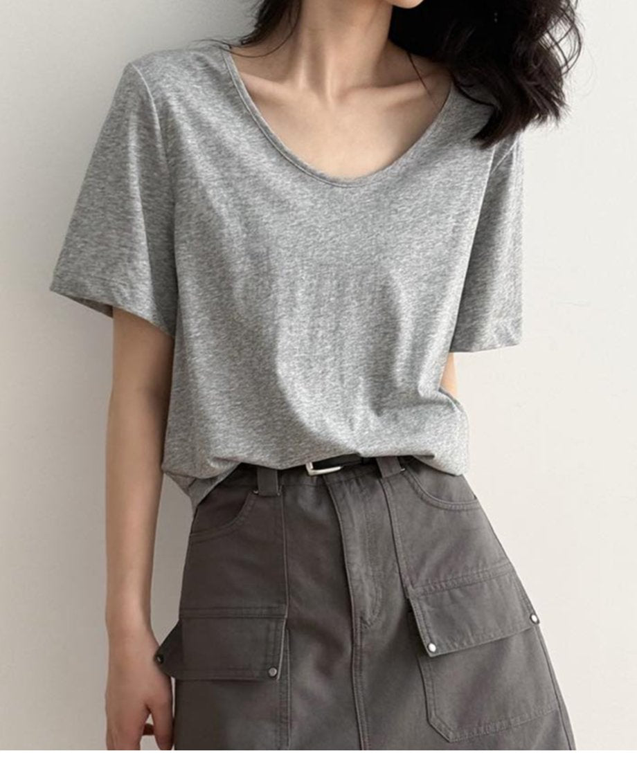 ライトグレーのTシャツを着用した女性の上半身。Tシャツをグレーのカーゴポケット付きミニスカートにタックインし、黒いベルトを締めている。
