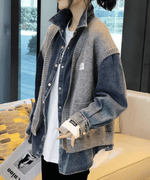 グレーのニットベストとデニムシャツを着て立っている女性の写真。