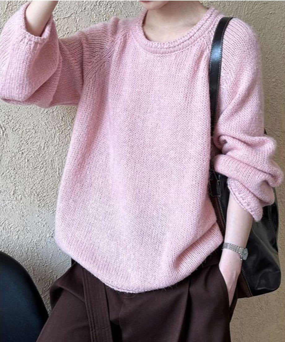 ピンクのローゲージニットを着用した上半身写真。こげ茶色のボトムスを履いており、全体的に優しい雰囲気のスタイリング。