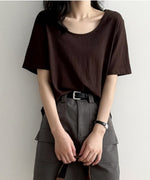 ブラウンのUネックTシャツを着用した女性の上半身。Tシャツをグレーのカーゴポケット付きミニスカートにタックインし、黒いベルトを締めている。