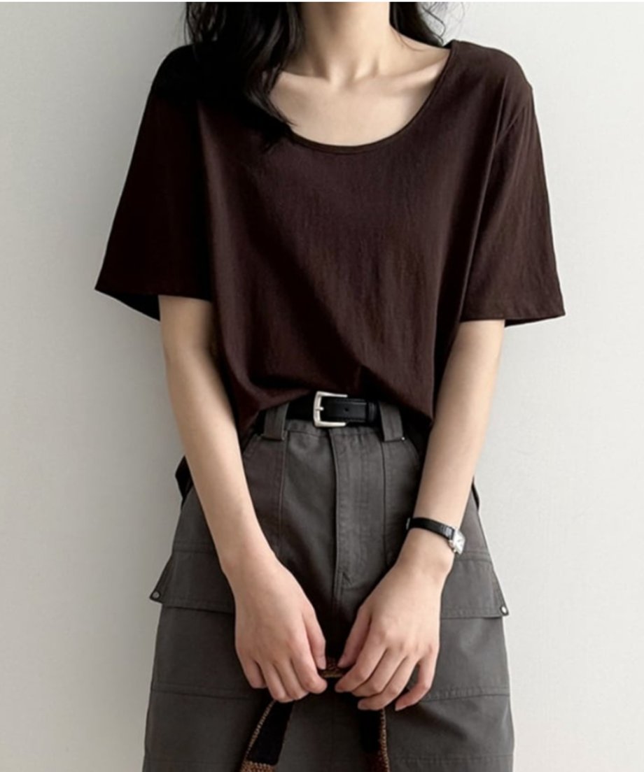 ブラウンのUネックTシャツを着用した女性の上半身。Tシャツをグレーのカーゴポケット付きミニスカートにタックインし、黒いベルトを締めている。