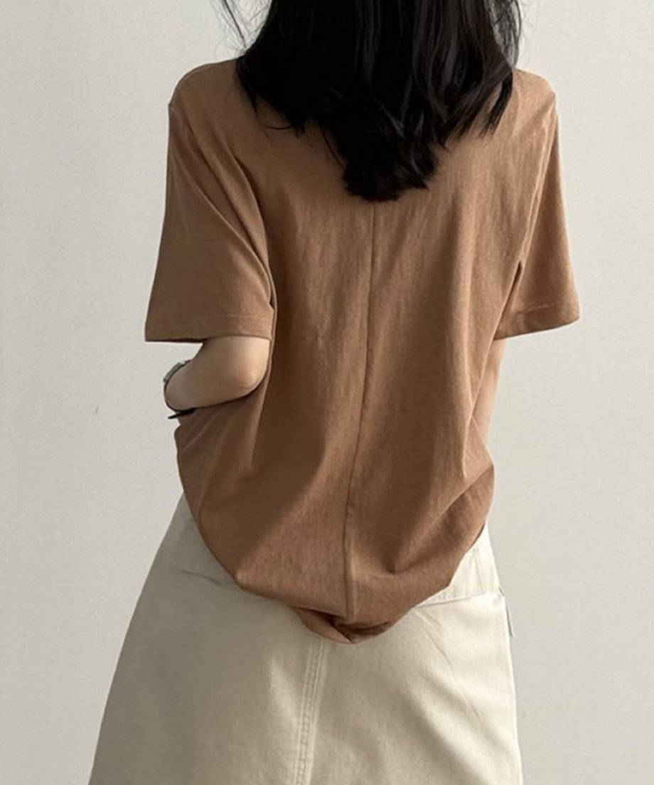 キャメルのUネックTシャツを着用した女性の上半身の後ろ姿。ベージュのボトムスとコーディネートした写真。