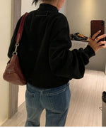 ブラックのラージポケットブルゾンを着用し、ハイウエストのストレートデニムを履いた女性の後ろ姿。短めの着丈とボリューム袖が見える。