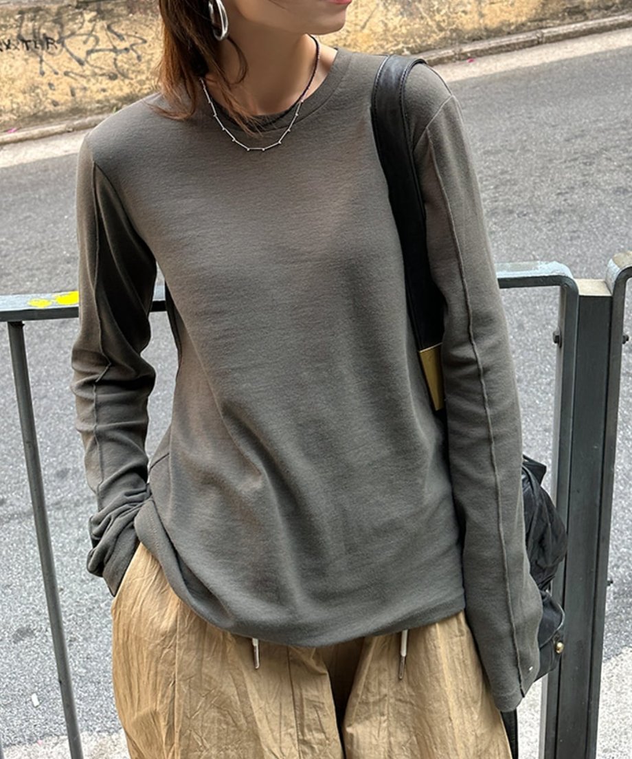 グレーのアウトシームロングTシャツを着て、ベージュのドローストリングパンツを着用した人物のバストアップ。