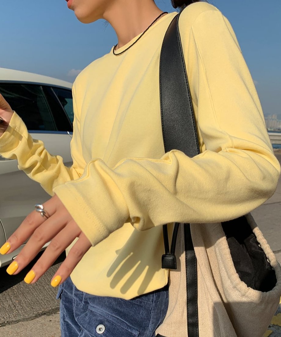イエローのアウトシームロングTシャツのバストアップ。袖が少し捲れており、アウトシーム（外縫い）のディテールが見える。