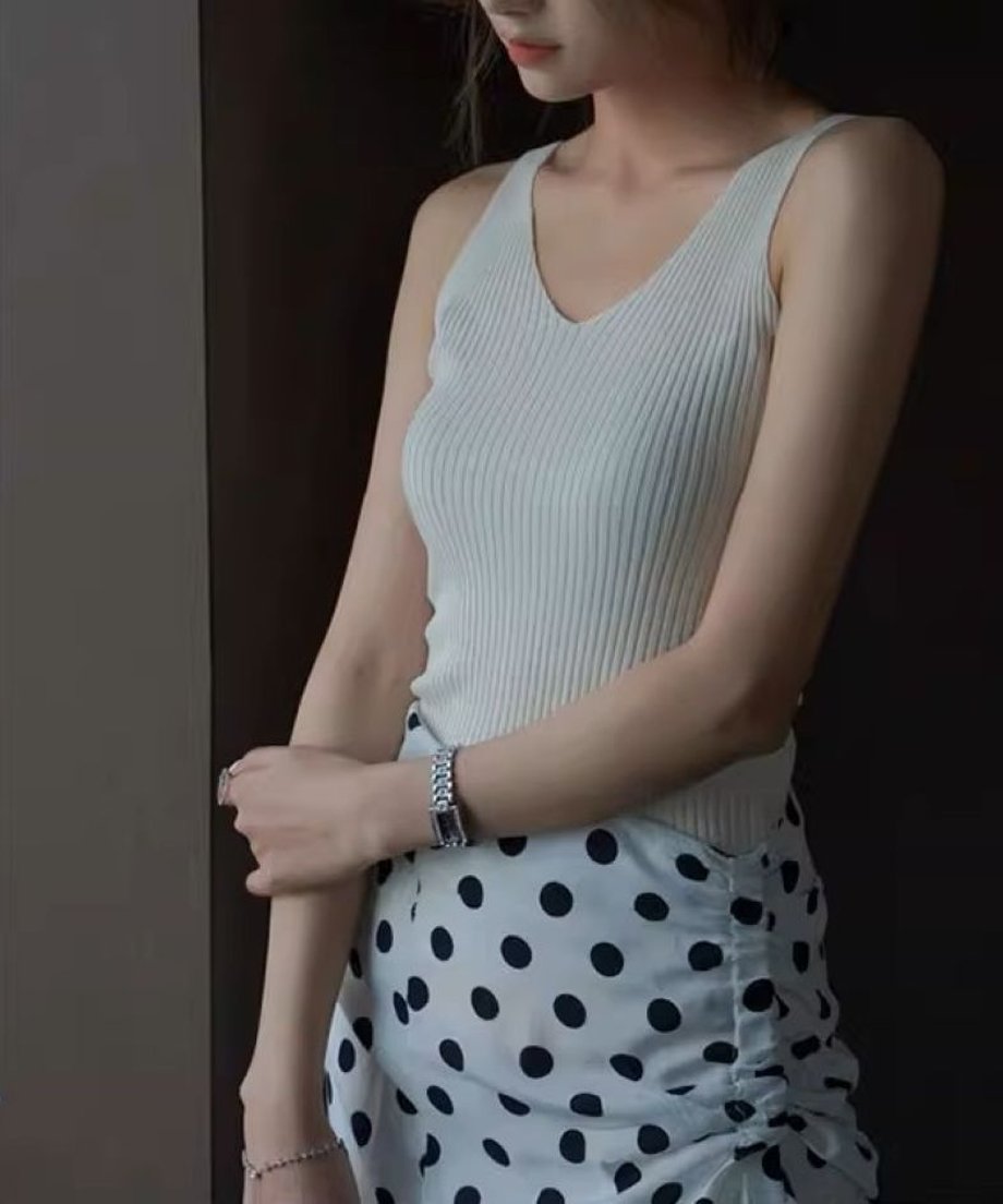ベージュのリブタンクトップを着た女性がドット柄スカートを合わせている画像。