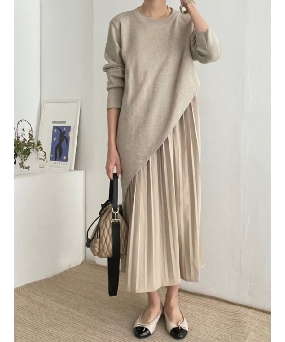 ベージュのアシンメトリーニットとプリーツスカートのドレスを着用した女性