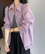 パープルのリボンシアーシャツを羽織り、グレーのインナーと黒いスカートを合わせた女性の上半身画像。腕を組むようなポーズ。