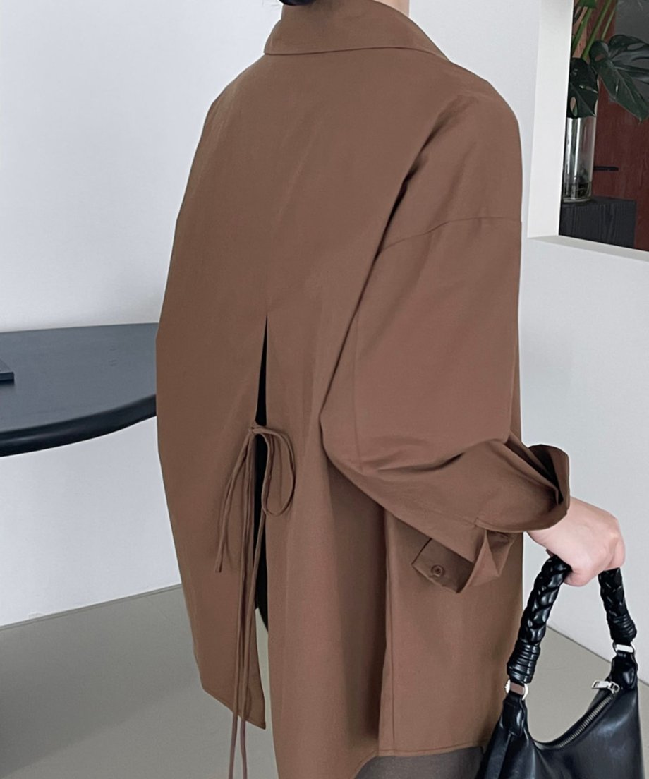 ブラウンのバックスリットシャツを後ろから見た着用画像。スリットと垂れ下がったリボンが特徴。