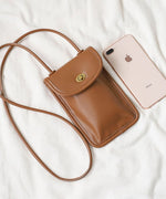 ャメル色のスマホポーチとiPhoneを並べて、サイズ感を比較しているカット。