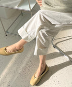 白いパンツとピスタチオカラーのニットに、ベージュのスクエアトゥバレエシューを履いている女性。