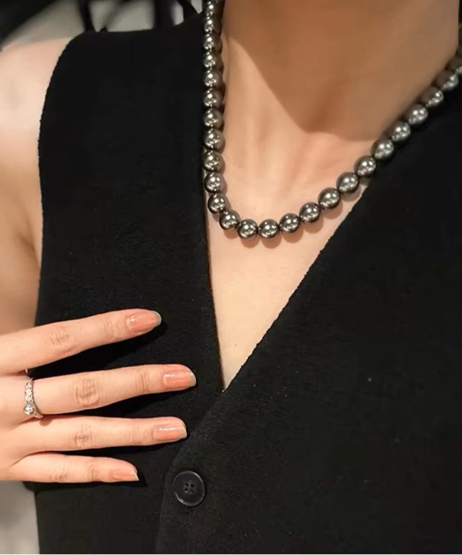 黒いトップスに合わせたブラックパールネックレス。